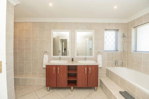 a bathroom with two sinks and a bath tub at Brooklands Sanctuary in Gqeberha