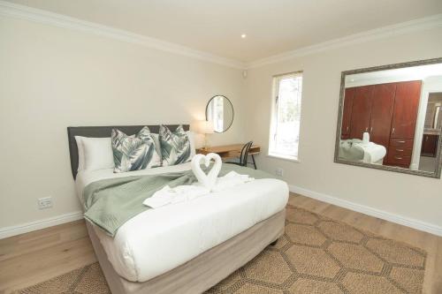 a bedroom with a large white bed with a mirror at Brooklands Sanctuary in Gqeberha