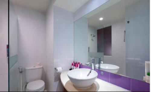 a bathroom with a sink and a toilet and a mirror at favehotel Solo Baru in Solo