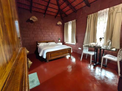 a bedroom with a bed and a table and chairs at Hidden Roots Sakleshpur in Hanbalu
