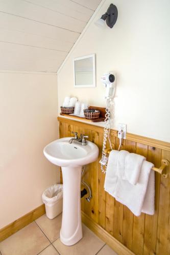 a bathroom with a sink and towels on a wall at Auberge Au Soleil Levant in Piopolis