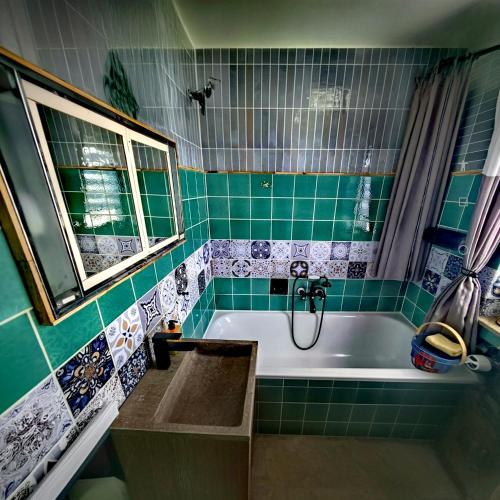 a green tiled bathroom with a tub and a window at Ferienhaus VILLA ZAUBERBLICK am Rennsteig Frankenwald FREISTEHEND naturnah HUNDEFREUNDLICH eingezäunt in Ludwigsstadt