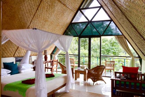 a bedroom with a bed in a room with windows at Mbeliling Mountain Ecolodge in Noca