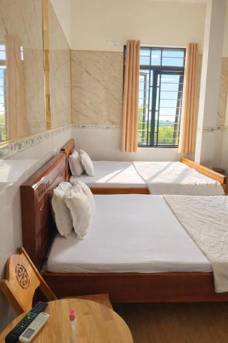 a room with three beds and a table and a window at Tam Ky XO Hotel in Tam Kỳ
