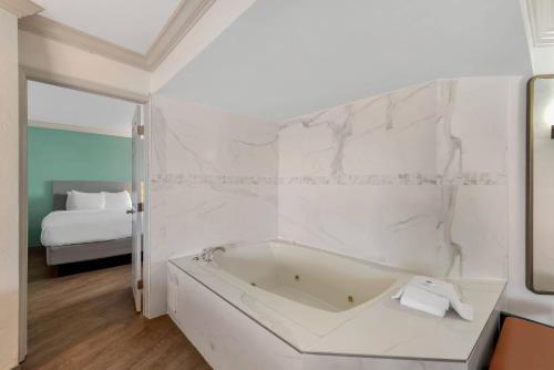 a white bathroom with a tub and a bed at Comfort Inn & Suites Ormond Beach Oceanfront in Ormond Beach