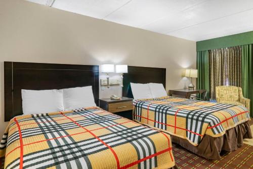 a hotel room with two beds and a chair at Rodeway Inn Clearwater-Dunedin in Clearwater