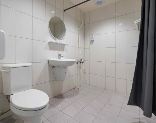 a white bathroom with a toilet and a sink at Hwa Nan Hotel in Yongkang