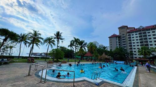 a group of people in a swimming pool at a resort at Beachfront Bliss Sea View Glory Beach PD Homestay in Port Dickson