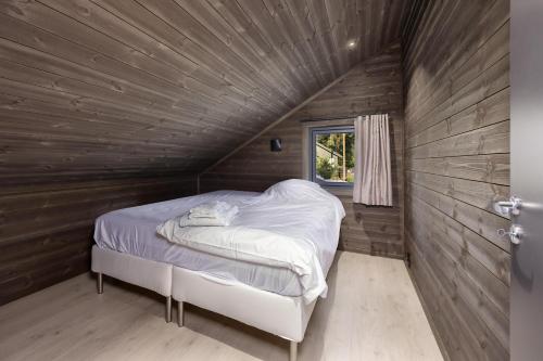a bed in a room with a wooden wall at Berre Veit 6p in Vradal