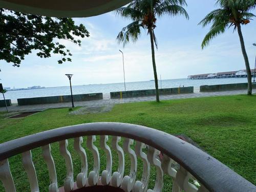 a white bench sitting in front of the ocean at Beachfront Bliss Sea View Glory Beach PD Homestay in Port Dickson