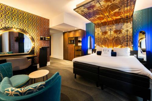 a hotel room with a bed and chairs and a mirror at NYX Hotel Amsterdam Rembrandt Square in Amsterdam