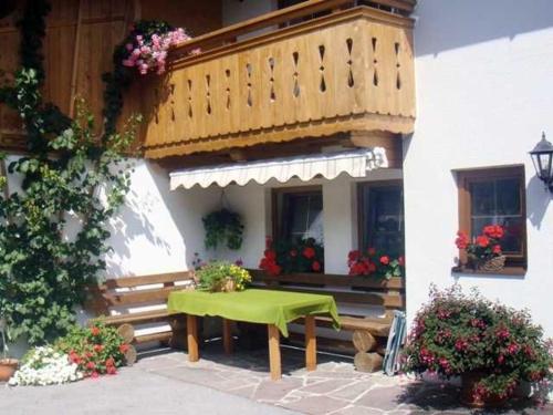 a green table in front of a building with a balcony at Lippenhof in Leutasch