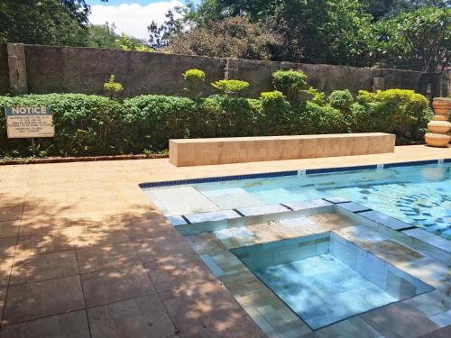 a swimming pool with a bench in a yard at Inkindaba Guest Lodge in Victoria Falls