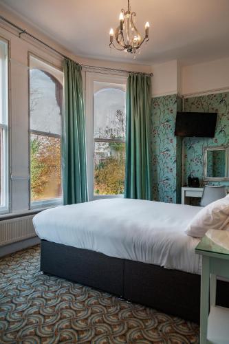 a bedroom with a large bed and two windows at Sefton Park Hotel in Liverpool