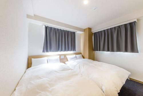 a large white bed in a room with windows at Hopetree OSAKA GRAND in Osaka