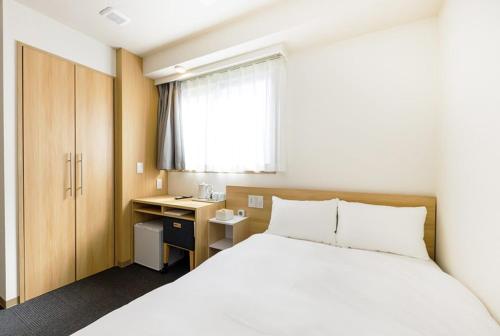 a bedroom with a bed and a desk and a window at Hopetree OSAKA GRAND in Osaka