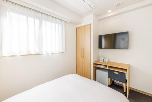 a bedroom with a bed and a desk with a television at Hopetree OSAKA GRAND in Osaka