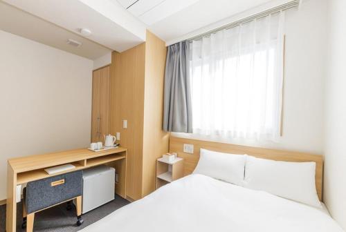 a bedroom with a bed and a desk and a window at Hopetree OSAKA GRAND in Osaka