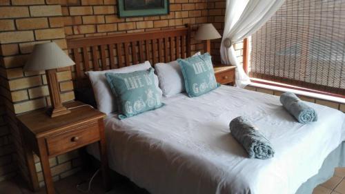 a bedroom with a bed with blue pillows and a window at Timber and Tide in Cannon Rocks