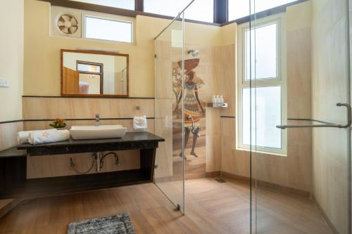 a bathroom with a sink and a glass shower at SaffronStays Valleyfall in Kotagiri