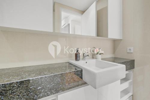 a white bathroom with a sink and a mirror at Nirasa by Kozystay - Paskal in Bandung