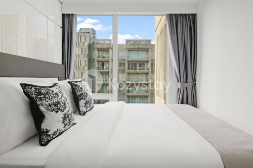 a white bed with pillows in front of a window at Nirasa by Kozystay - Paskal in Bandung