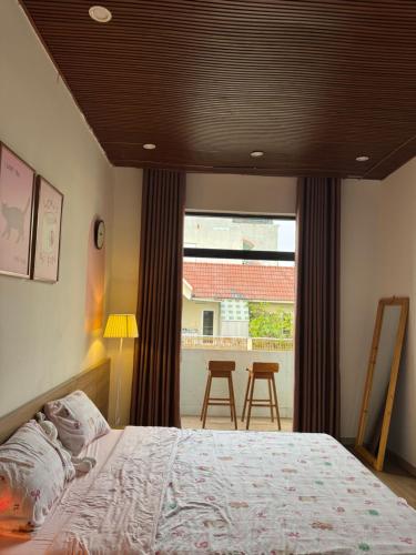 a bedroom with a bed and a view of a balcony at Nhà Bơ Homestay 2 in Danang