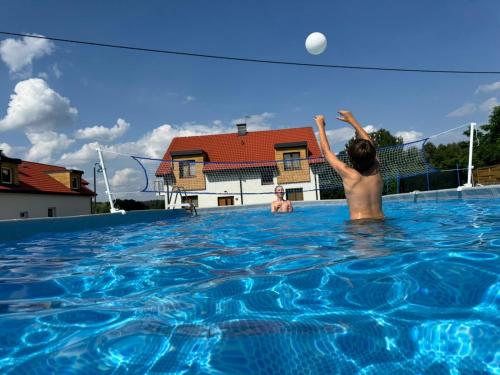 two boys playing with a frisbee in a swimming pool at Apartamenty Panoramic-Piecki in Piecki