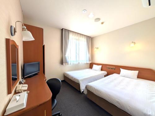 a hotel room with two beds and a desk at Suizenji Comfort Hotel in Kumamoto