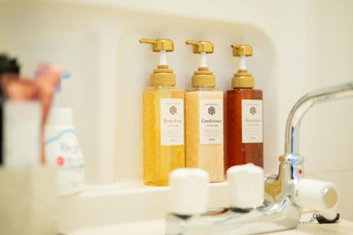 three bottles of soap sitting next to a sink at Happy Osaka City in Osaka