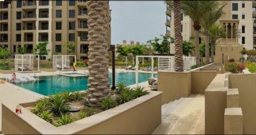a swimming pool with a palm tree in a resort at Nasma Luxury Stays - Fabulous Apartment With Balcony Near MJL's Souk in Dubai