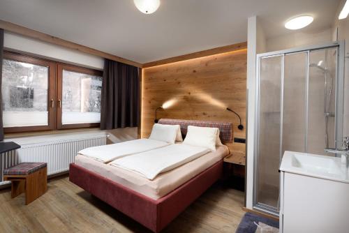 a bedroom with a bed and a shower and a sink at Hölzl Bed & Breakfast in Neukirchen am Großvenediger