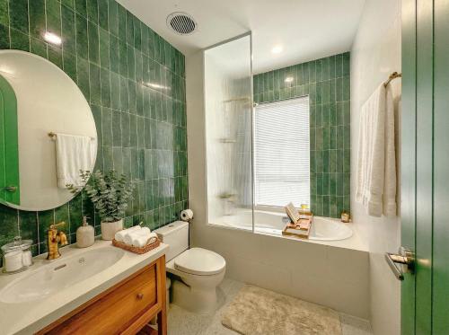 a green tiled bathroom with a toilet and a sink at Novaworld Phan Thiết - Alala Stay in Bình Sum