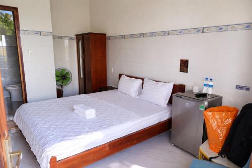 a small bedroom with a bed with white sheets at Sân Vườn Hotel Khánh Hòa in Ninh Hòa