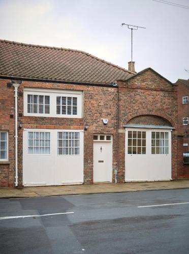 a brick building with two white garage doors at Fantastic Grade II listed renovated coach house in Hull