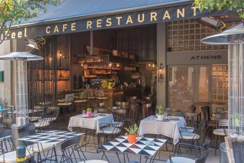 a cafe restaurant with tables and chairs in front of it at iFeel Athens Suites in Athens