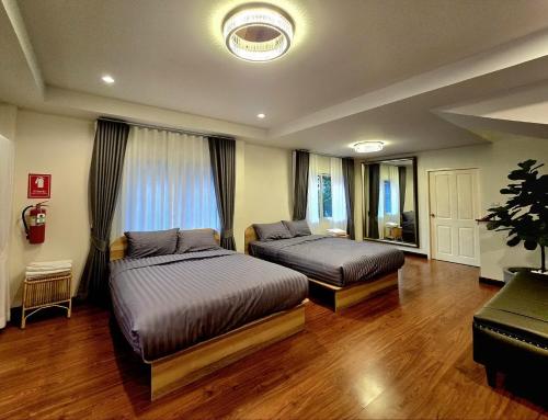 a bedroom with two beds and a large window at The Atlas hostel Muang Thong Thani in Thung Si Kan