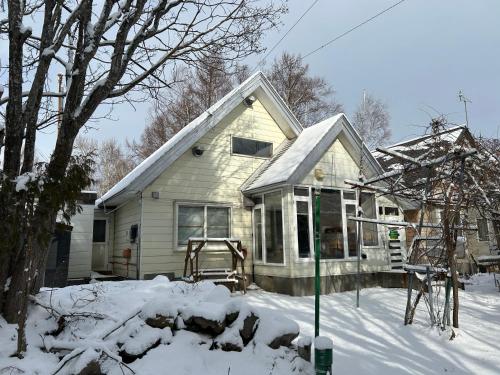 a house with snow on the ground in front of it at 北海道ゲストハウス川湯温泉6丁目 in Kawayu