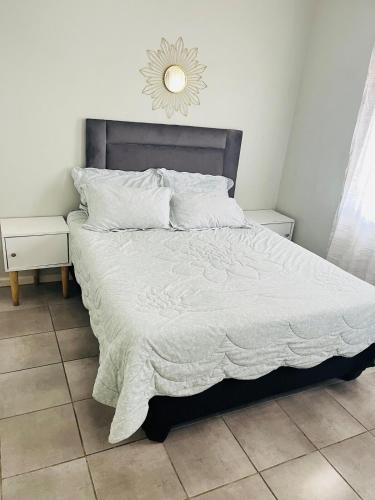 a bed with a white blanket and a mirror on the wall at Valley Escape in Cape Town