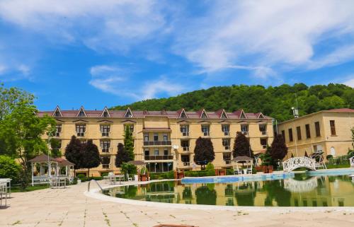 a large building with a pond in front of it at Gabala Yeddi Gozel Hotel in Gabala