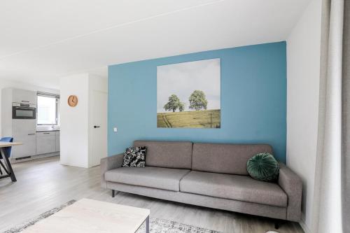 a living room with a couch and a blue wall at Sfeervol wellnesshuis met privé sauna en tuin in Ewijk