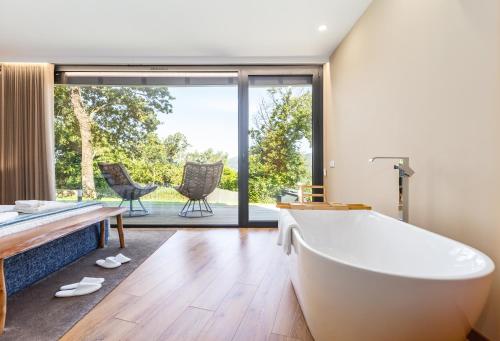 a bathroom with a tub and a patio with chairs at Casas De Bouro 3 Casa Do Alecrim in Terras de Bouro