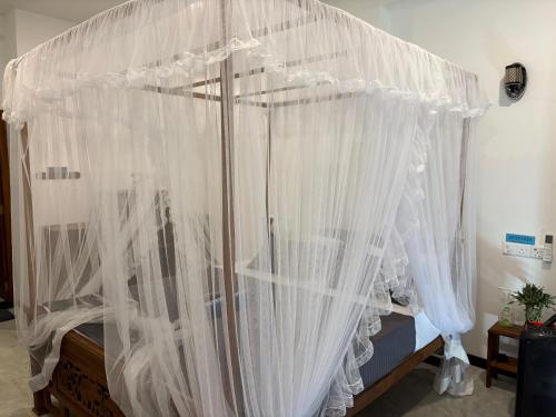 a bed with white mosquito netting on it at Minuda Villa in Kamburugamuwa