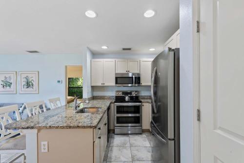 a kitchen with a stainless steel refrigerator and appliances at Le Monaco - 1 BR Romantic Condo! Getaway Steps from 5th Ave S Stylish Coastal Retreat with King Bed Beach Access and Prime Location, Near Dining Shopping and Sunset Views! in Naples