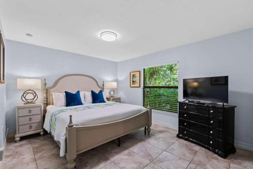 a bedroom with a bed and a flat screen tv at Le Monaco - 1 BR Romantic Condo! Getaway Steps from 5th Ave S Stylish Coastal Retreat with King Bed Beach Access and Prime Location, Near Dining Shopping and Sunset Views! in Naples