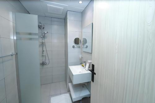 a white bathroom with a sink and a shower at Rose Holiday i3 روز هوليداي in Medina