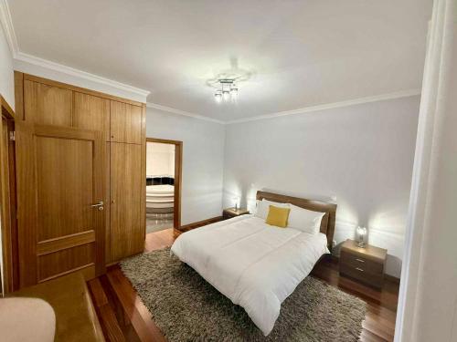 a bedroom with a white bed and a wooden door at Vista Verde in Estreito de Câmara de Lobos