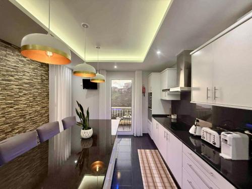 a kitchen with white cabinets and purple chairs at Vista Verde in Estreito de Câmara de Lobos