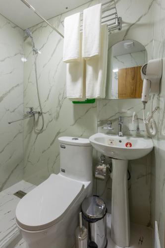 a white bathroom with a toilet and a sink at Zarafshon Garden Hotel in Bukhara