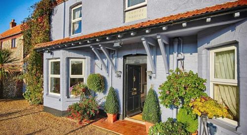 a blue house with plants on the side of it at Hooray Henrys Sheringham in Sheringham